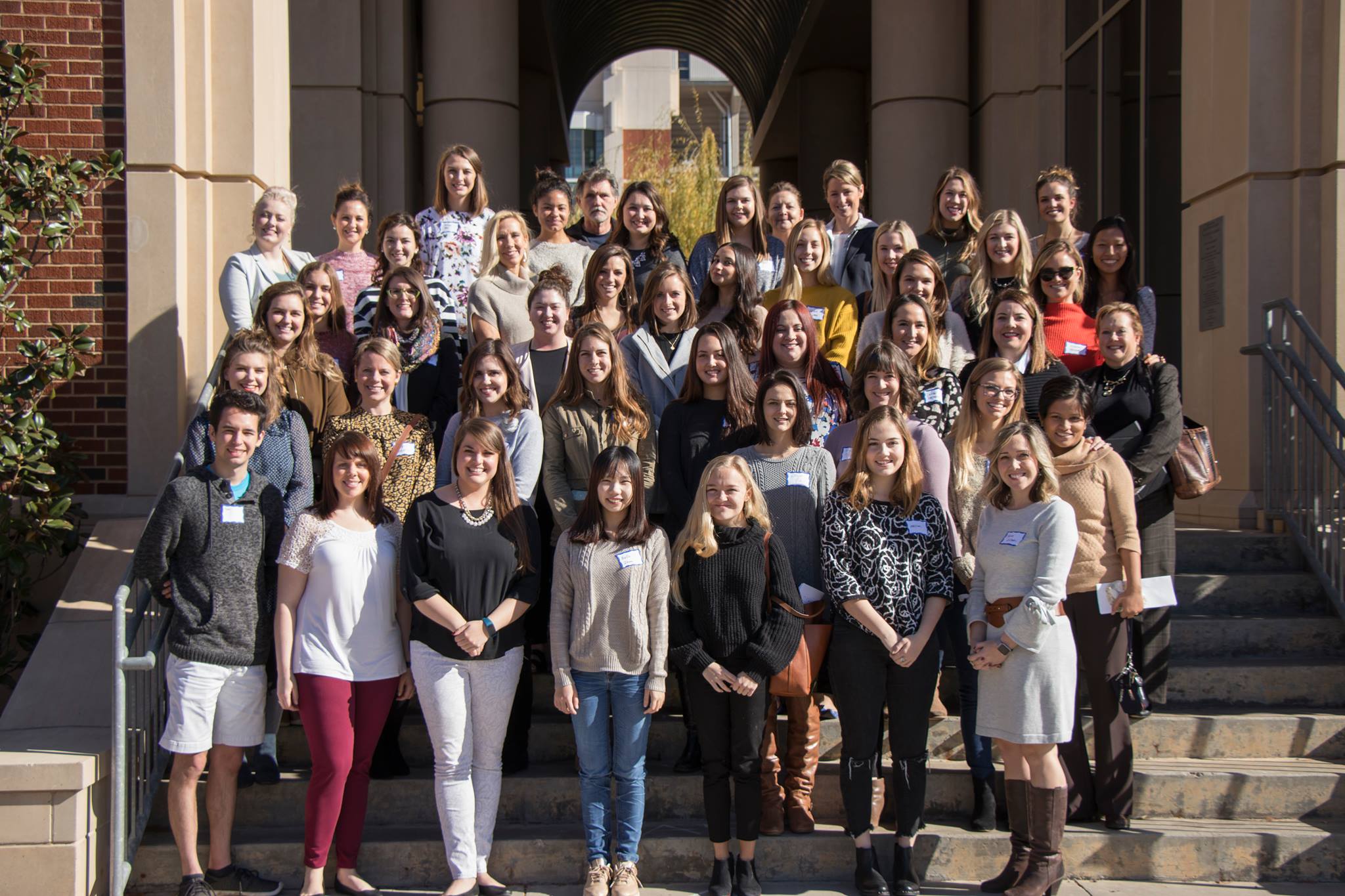 A group of people posing for a photo on the stairs of Gould Hall.