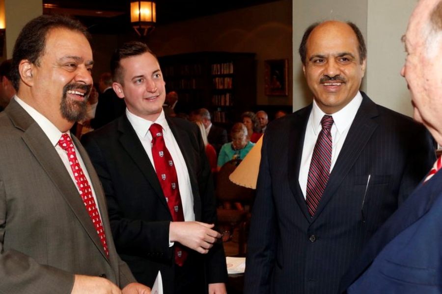 Four men in suits and ties standing in a conversation