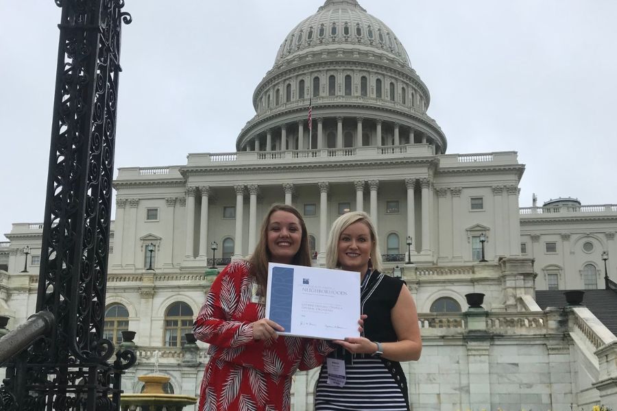 Rebecca Blaine pictured with coworker holding A P A award in front of U S capitol building.
