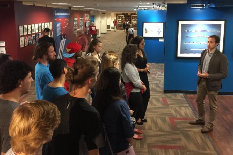 A curator talking to a group of students in a gallery of an exhibition