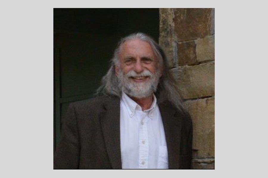 Headshot of dave boeck in a white shirt and brown blazer long grey hair and a beard