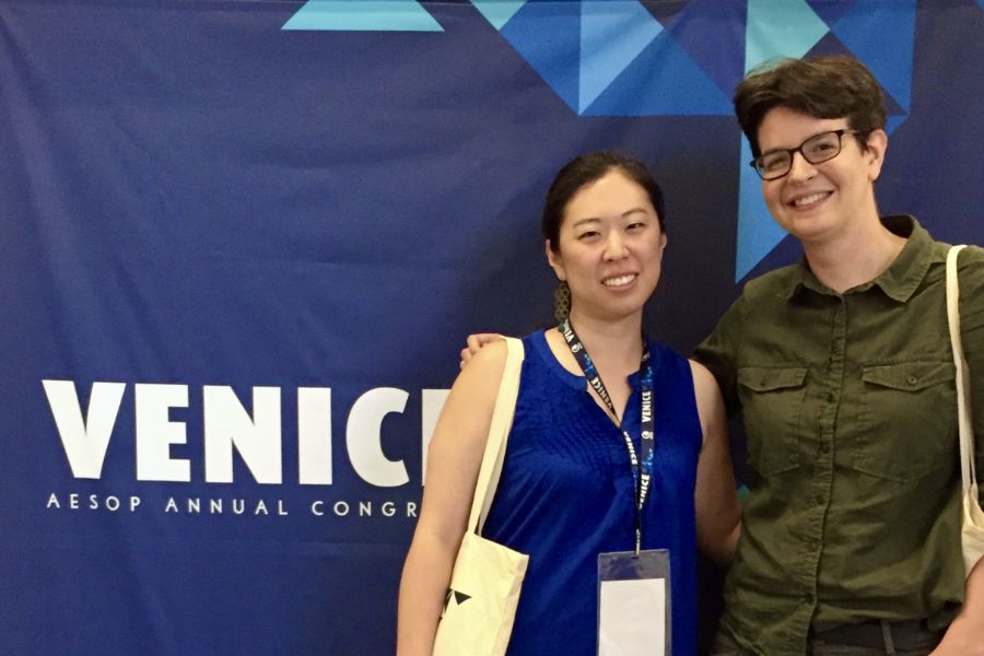 Professor C. Aujean Lee posing for a photo with another person in front of a conference banner