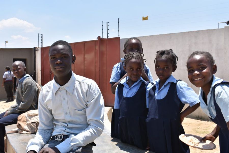 Five school children posing for a photograph outside with uniforms