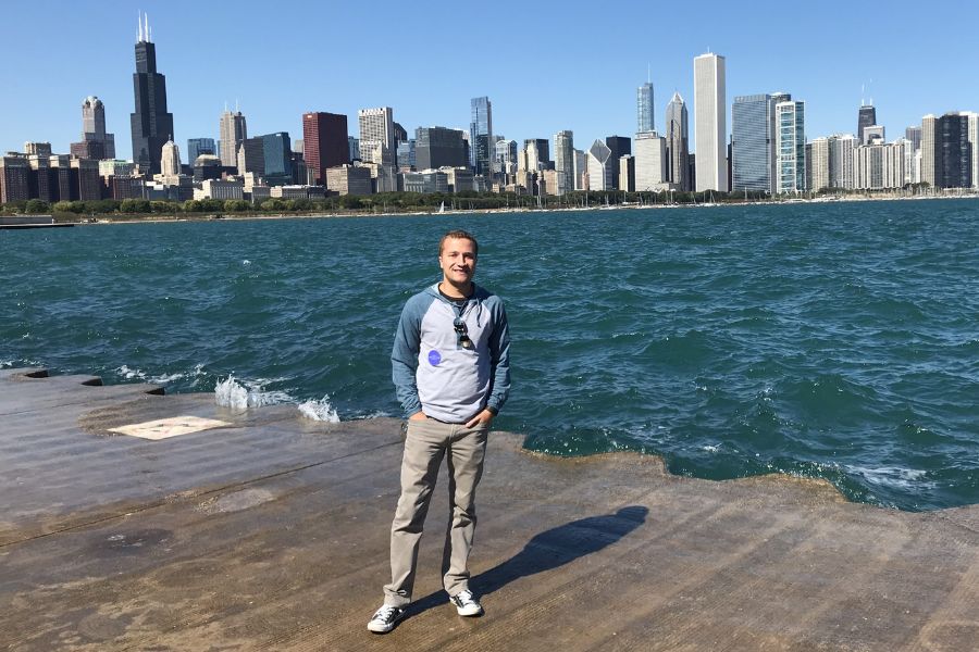 Chris Poage standing on doc with dense city scape in the background.