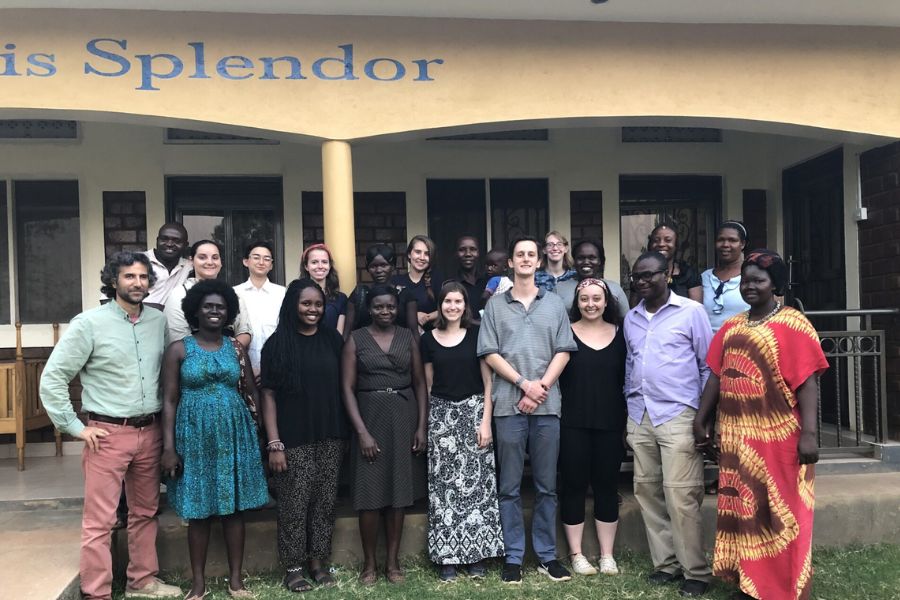 A co ed group stands for a photo outdoors with locals