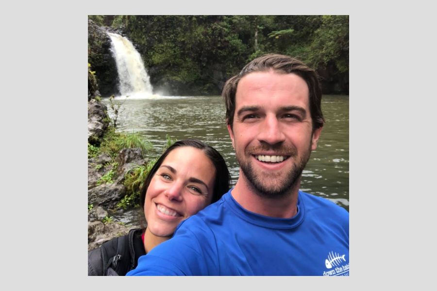 A selfie of Alex Tyler and a woman on his shoulder in front of a waterfall