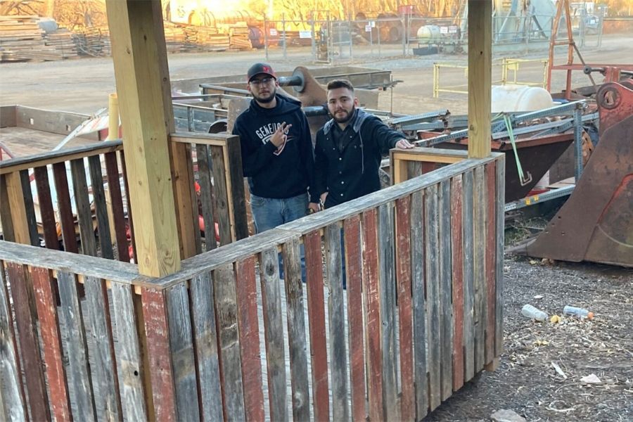 Two students with a shelter made from salvaged materials.