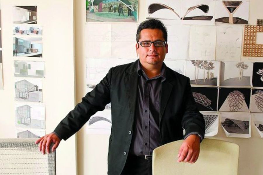 Man standing in front of architectural drawings and models on wall