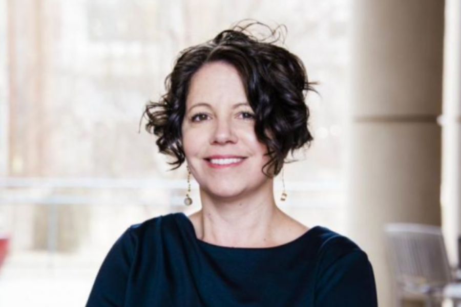 Portrait of Stephanie Pilat, Architecture Division Director, smiling indoors and wearing a dark top.