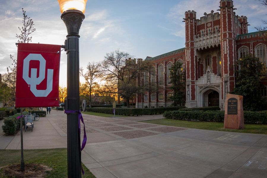 University of Oklahoma library building with an OU banner along a campus walkway.