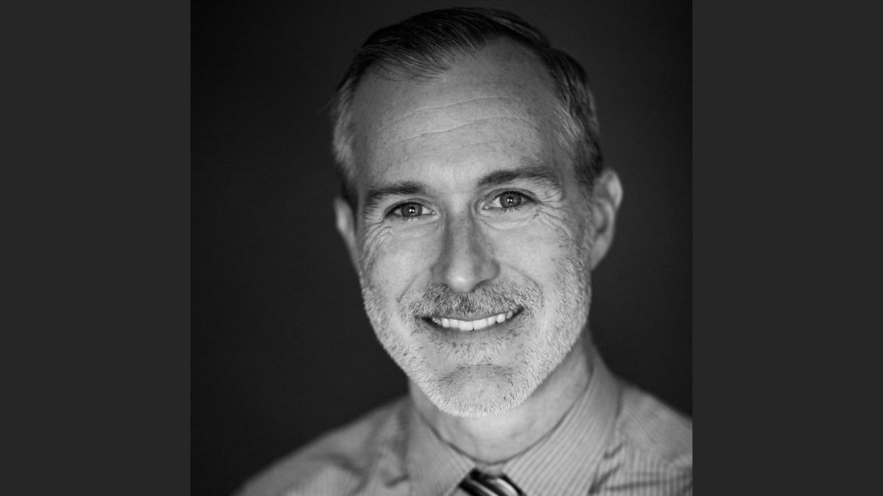 Black-and-white portrait of Dr. Bryce Lowery smiling against a dark background.
