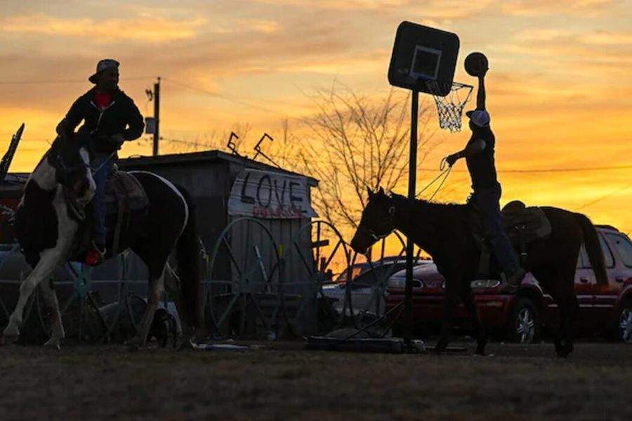 Two men playing basketball on horseback.