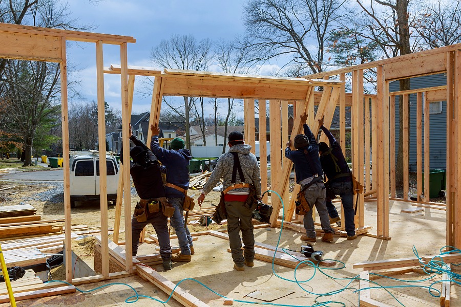 Construction works put up a wood housing frame outside.