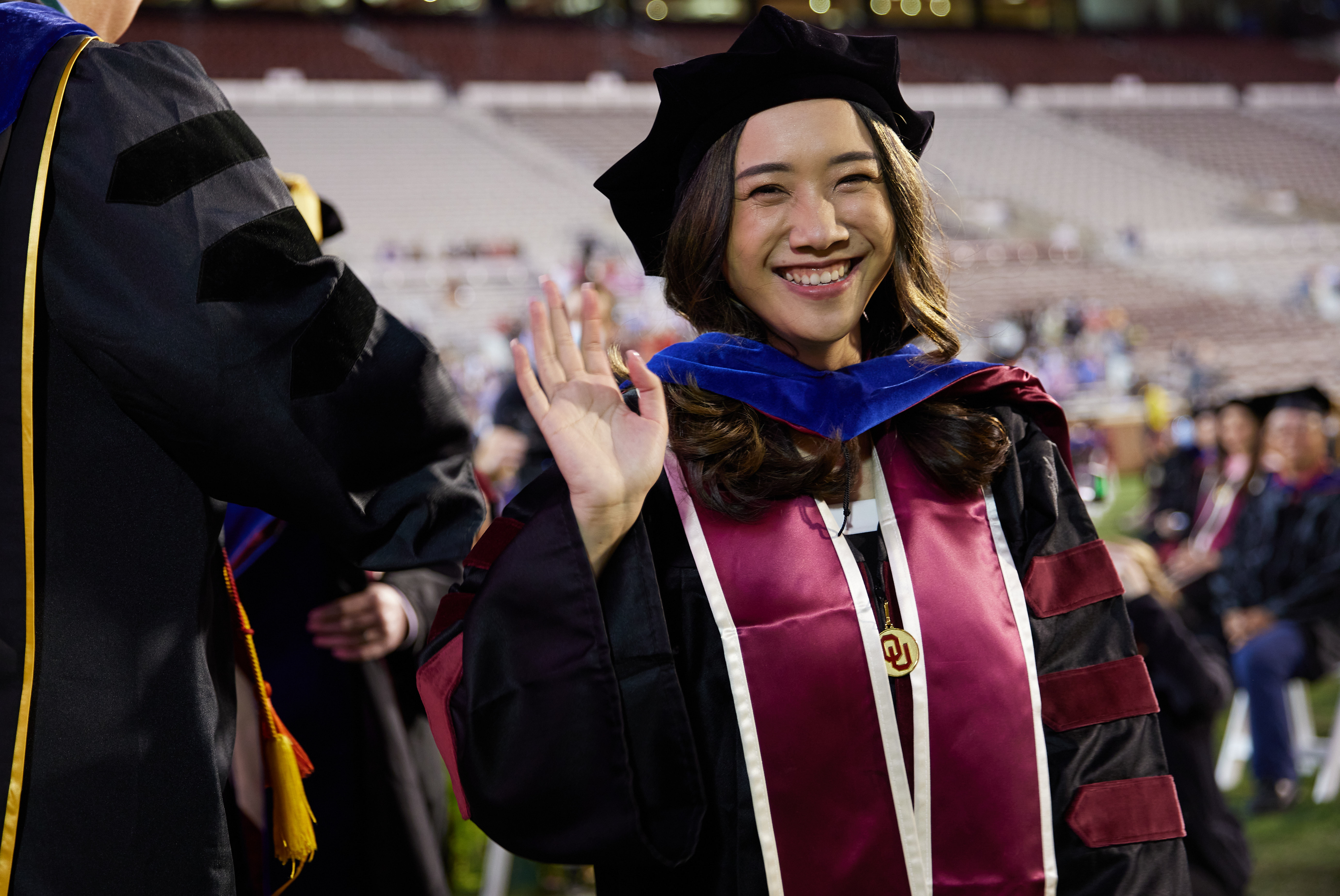 A female student graduating with their doctorate inside the OU football stadium.