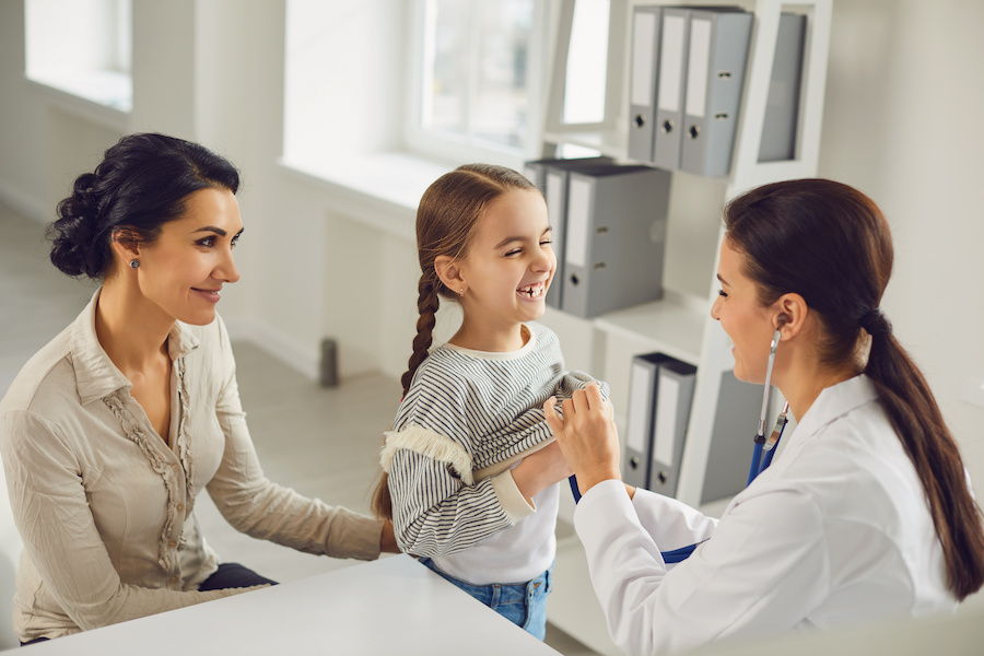 A doctor examining a child, with the parent next to the child.