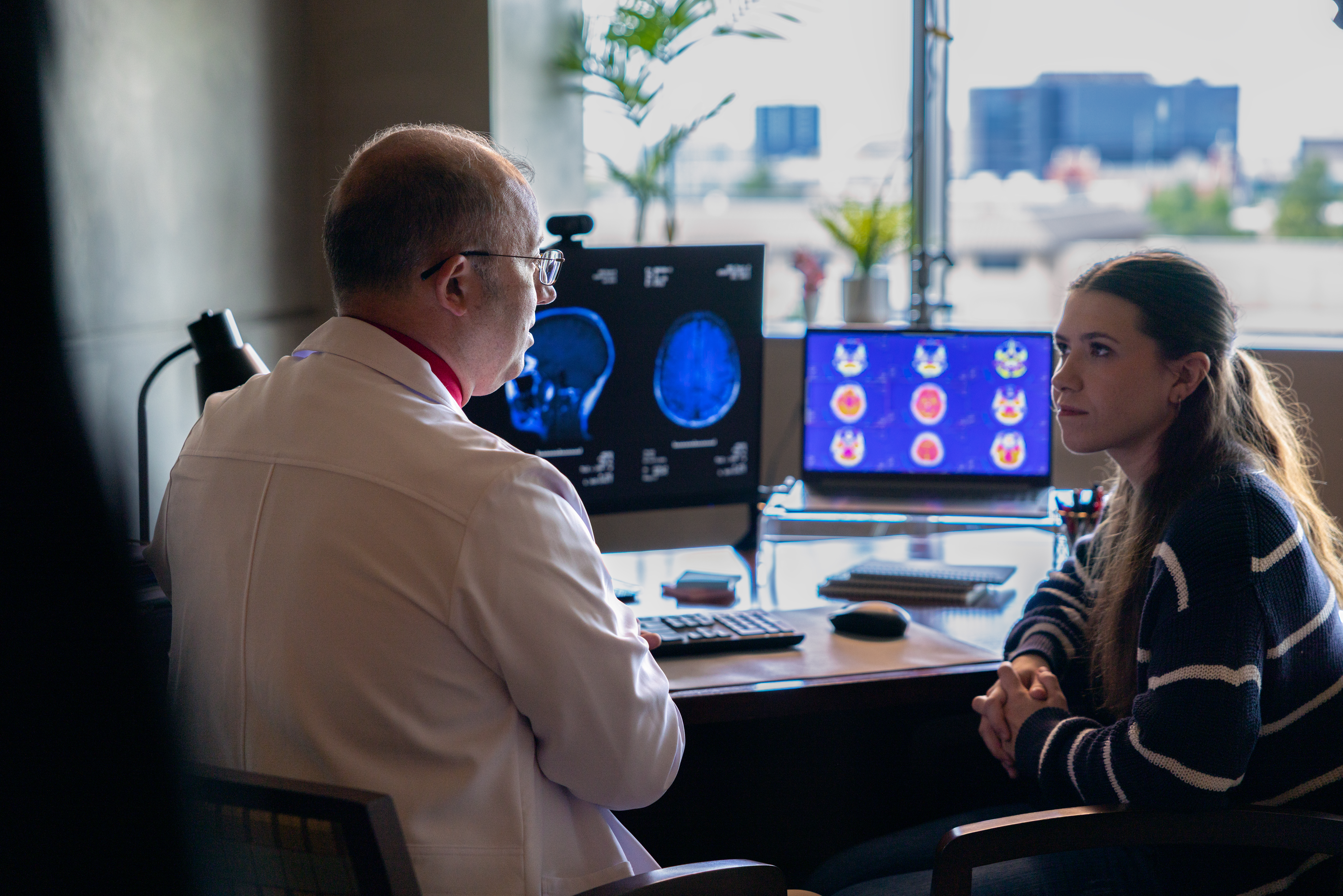 A doctor sitting at a desk, talking to a patient.