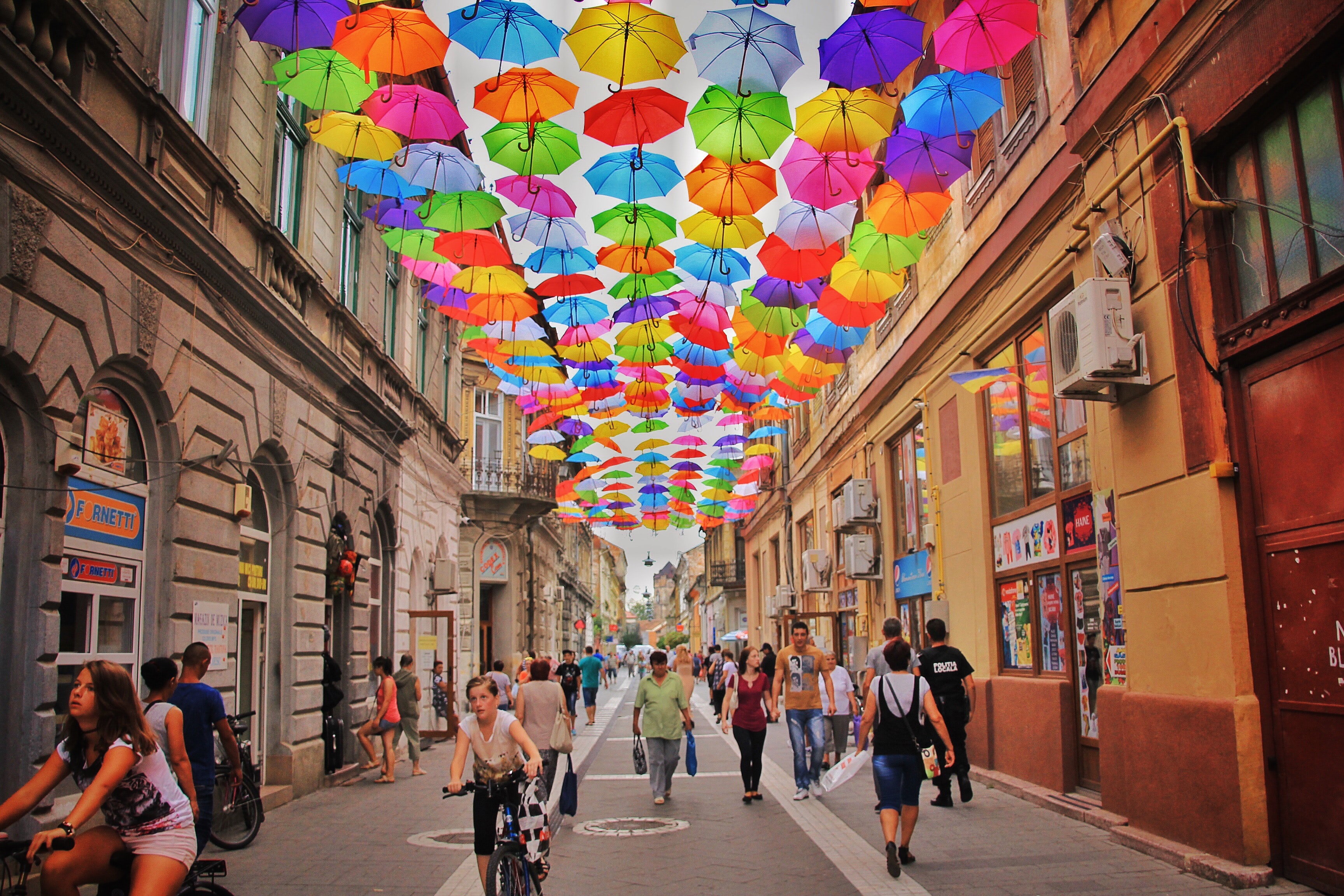 People walking down a colorful, Romanian street.