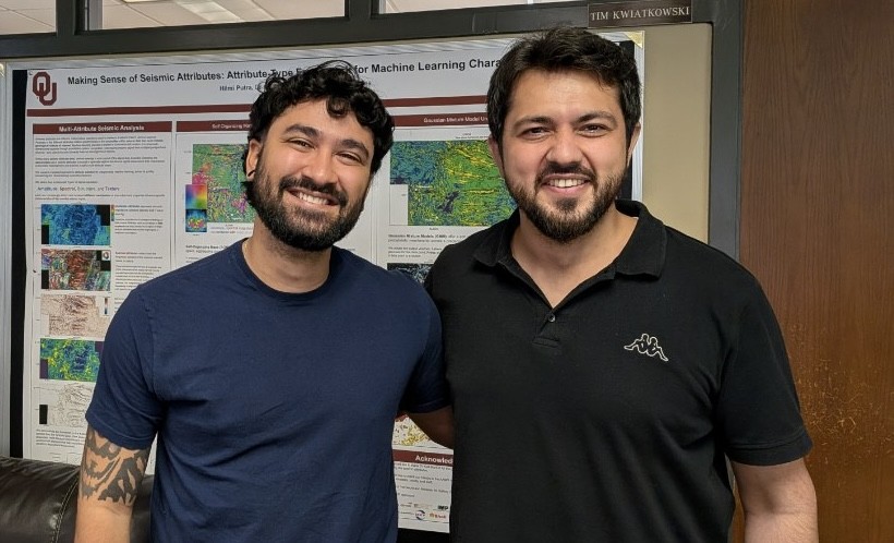 Nilo and Asad smiling standing in front of a seismic poster.