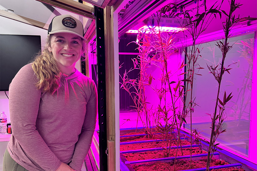 Hailey Seago standing next to plants growing beneath a grow light.