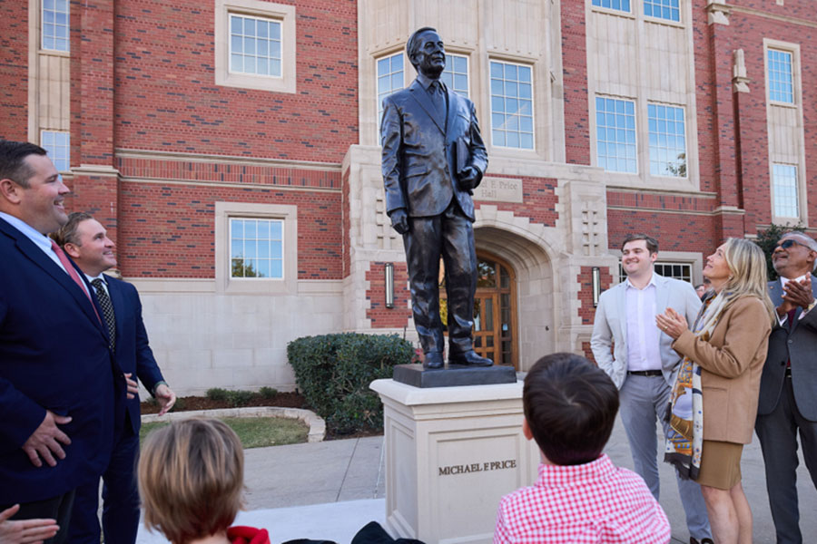 Individuals gathered around the recently unveiled Michael F Price statue.