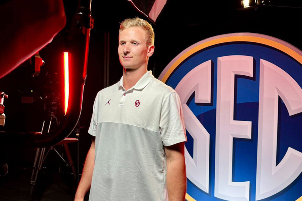 Luke Carrell stands in front of the SEC logo.