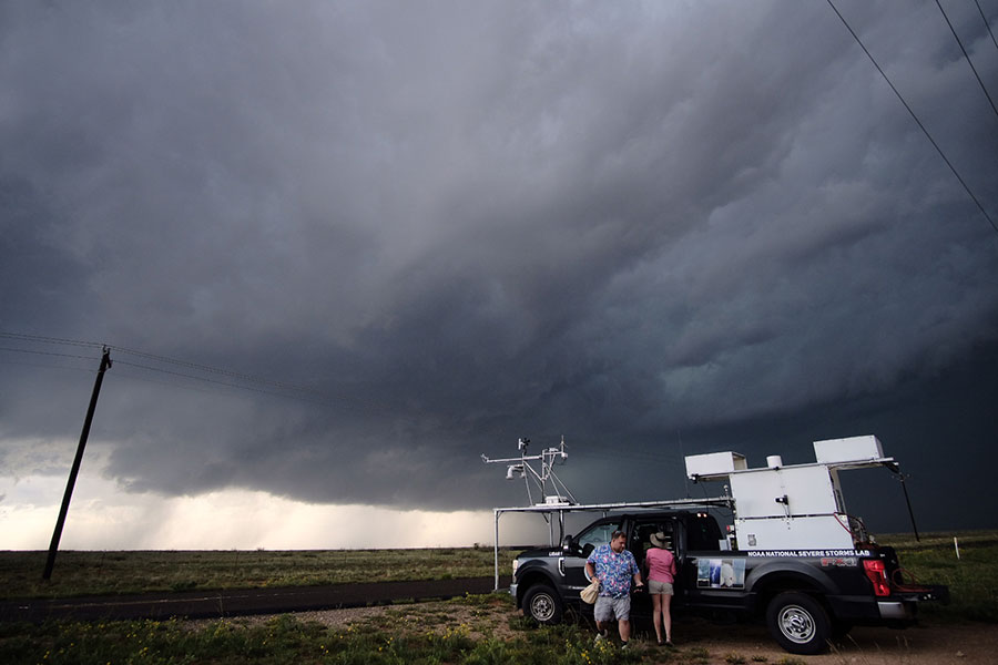 School of Meteorology students standing with a lidar truck in front of a looming cloud.