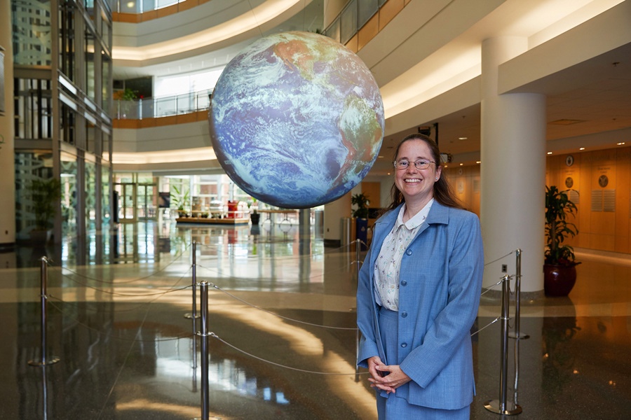 Amy McGovern, Ph.D., stands in front of the Science on a Sphere installation at the National Weather Center.