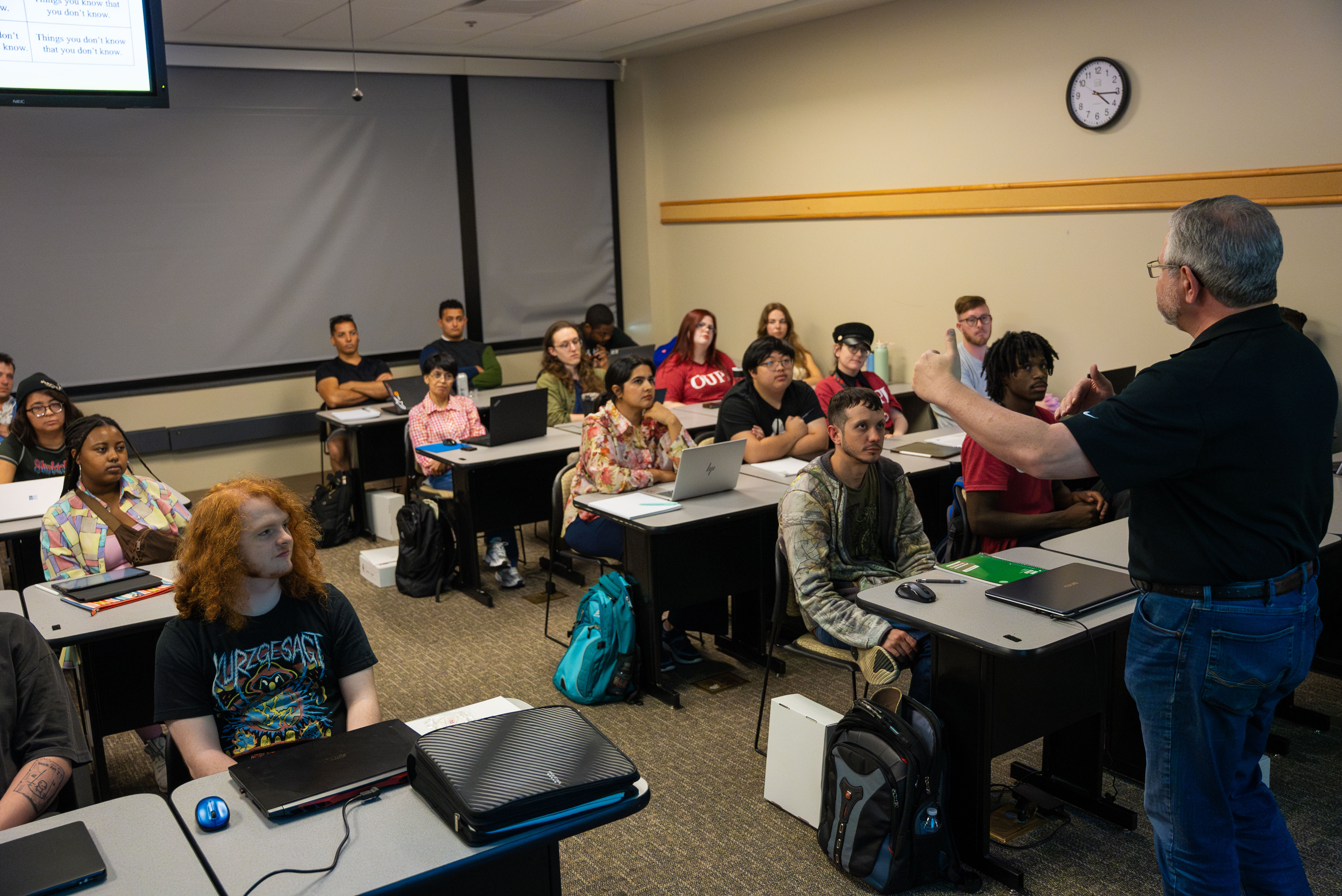 Students in a classroom look at their professor.