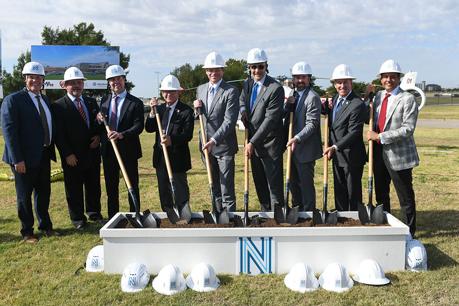 Community leaders dig shovels into a dirt at the groundbreaking ceremony.