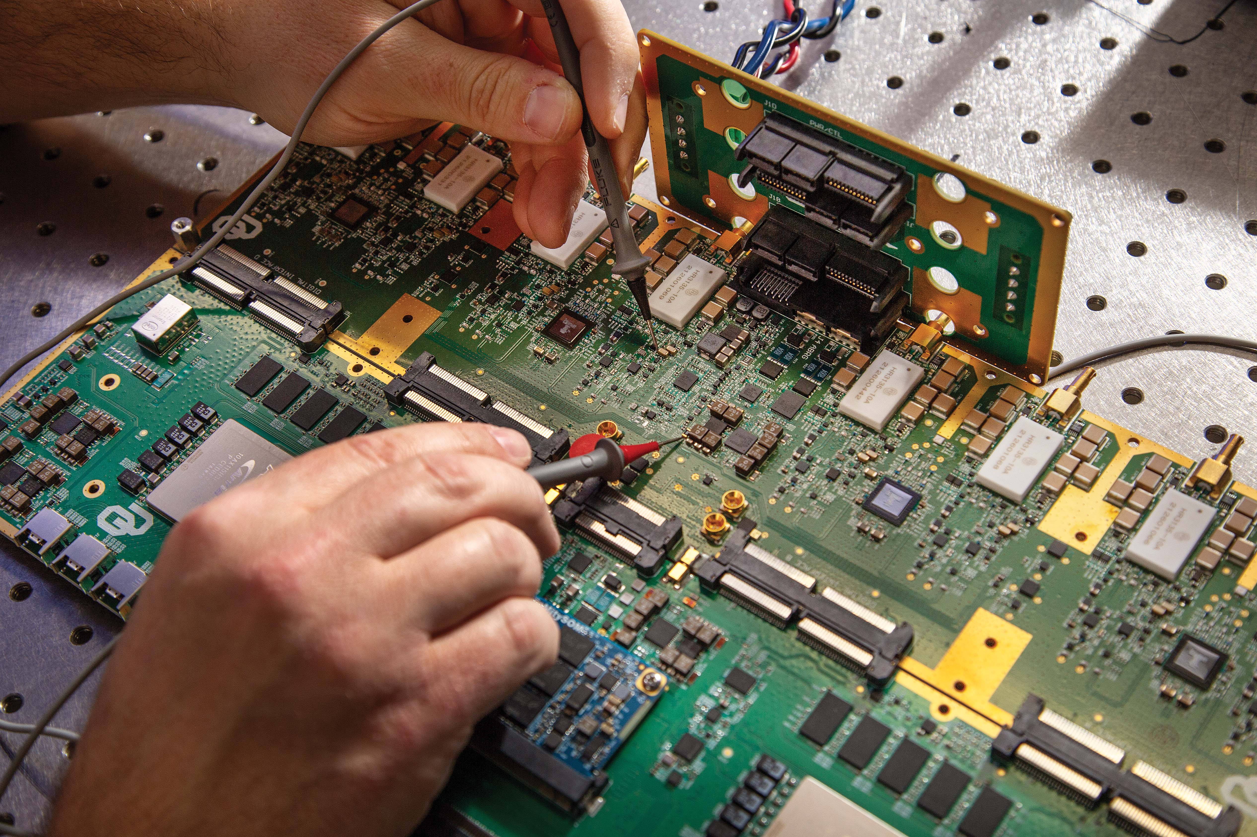 Two hands working on a circuit board.