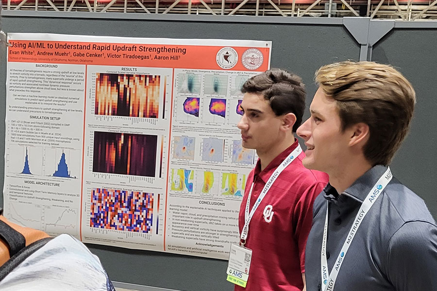 Two students stand in front of a poster presentation at a conference.