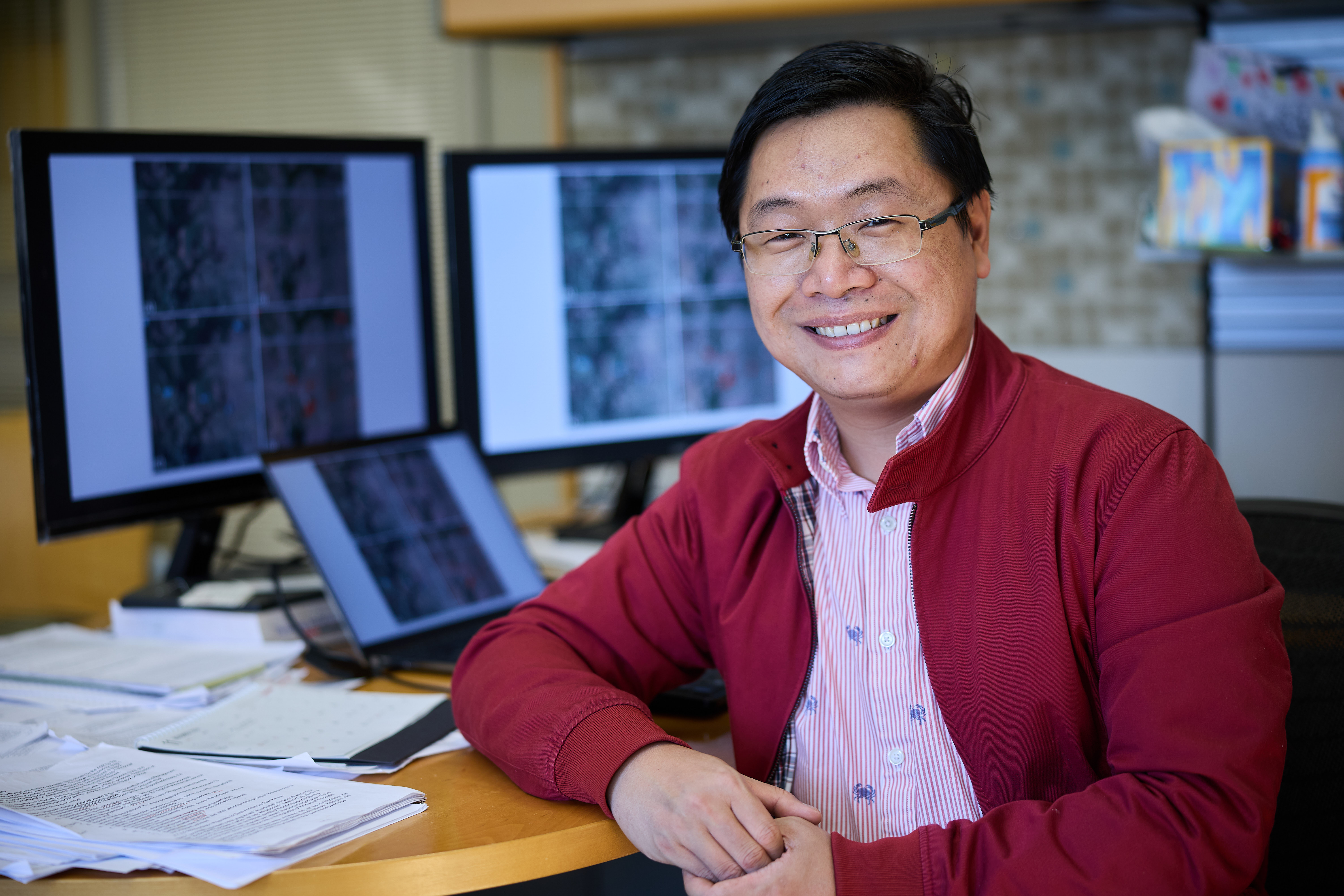 Chengbin Deng seated in front of computer screens depicting satellite data.