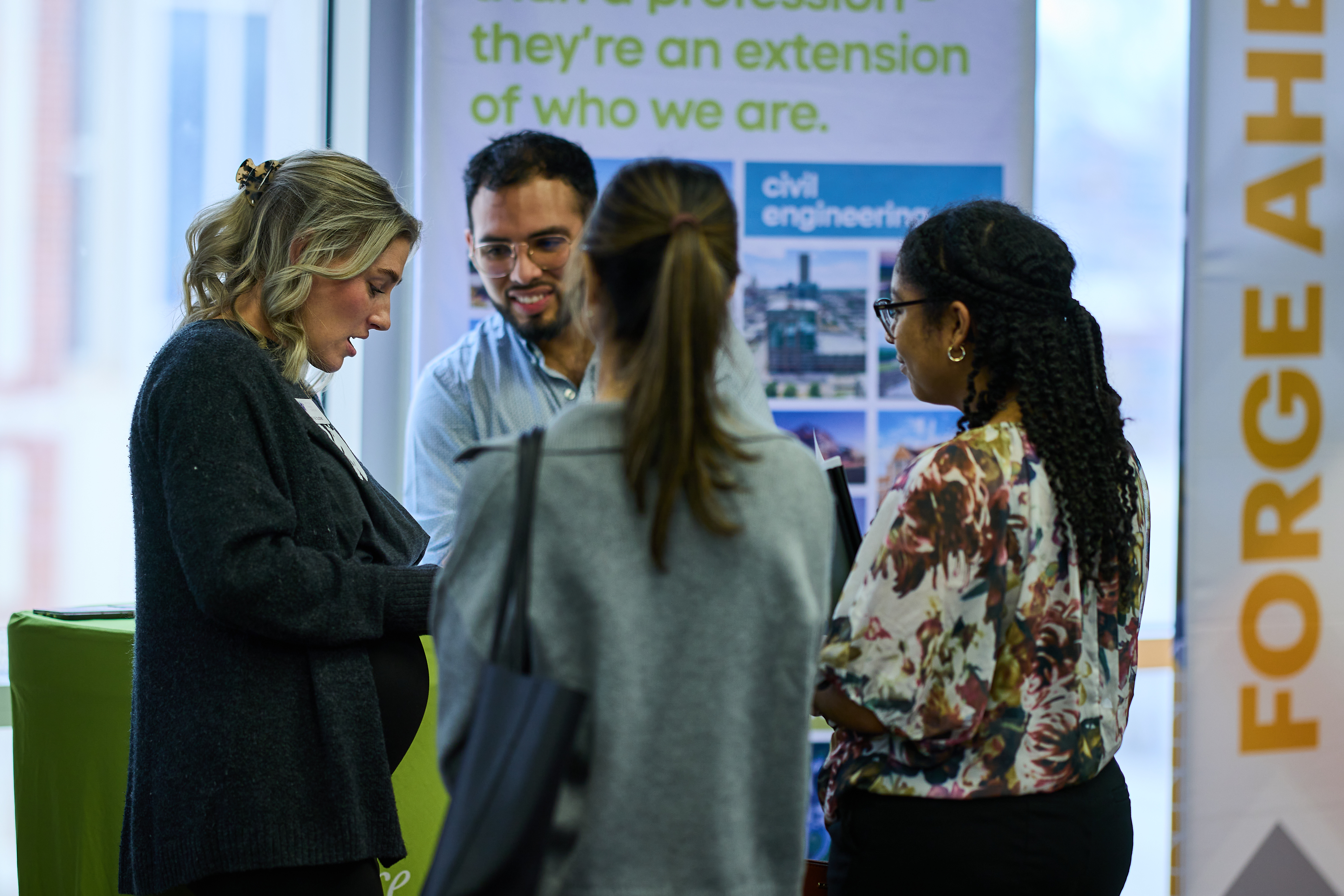 Students stand with a vendor at a career fair. 