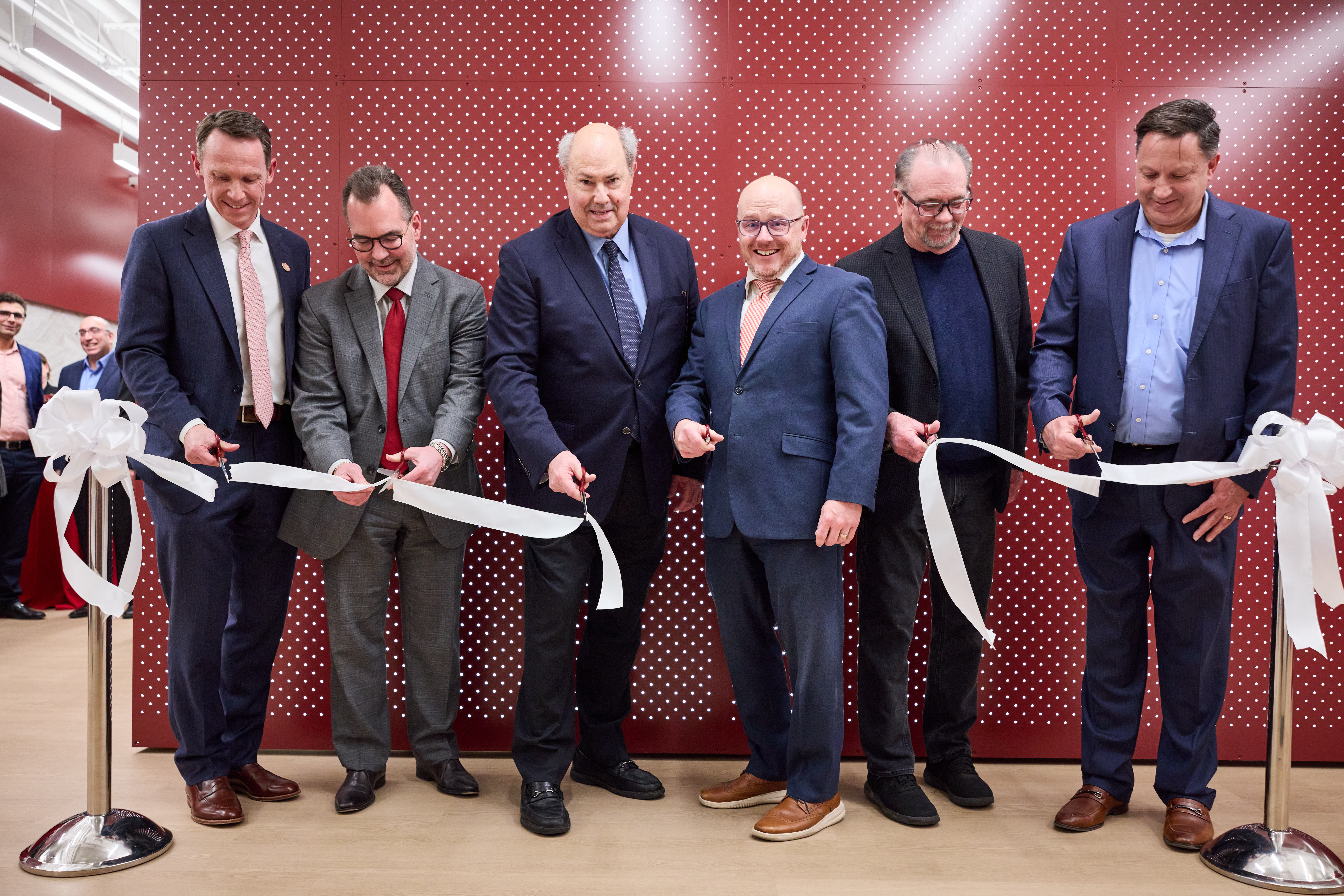 Ian Dunn, Darrin Akins, Gary Raskob, James Papin, Dean Myers and Paul Manzelli stand in a line cutting a white ribbon.