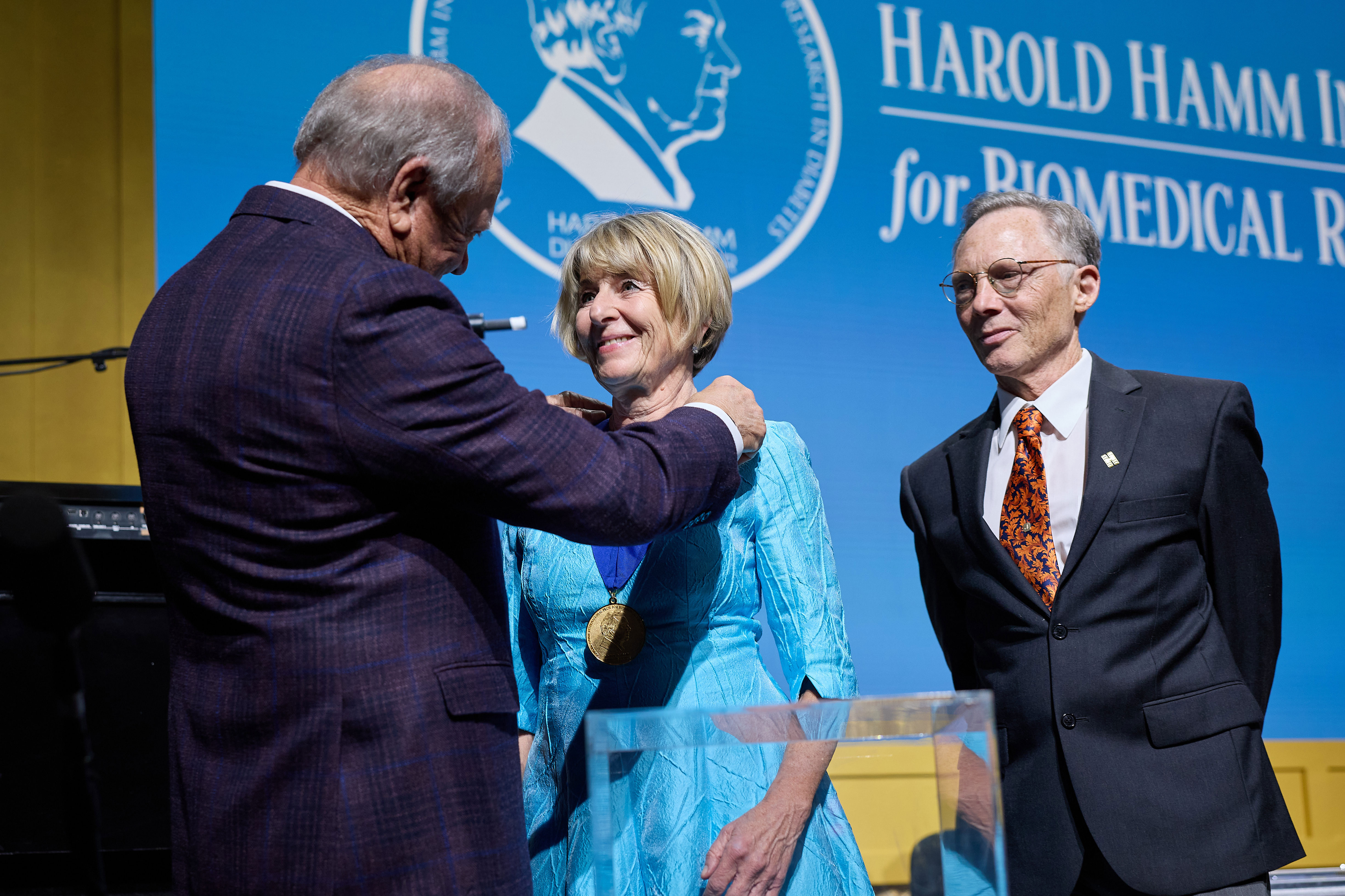 Harold Hamm presents a medal to Anette-Gabriele Ziegler as Jen Friedman watches.