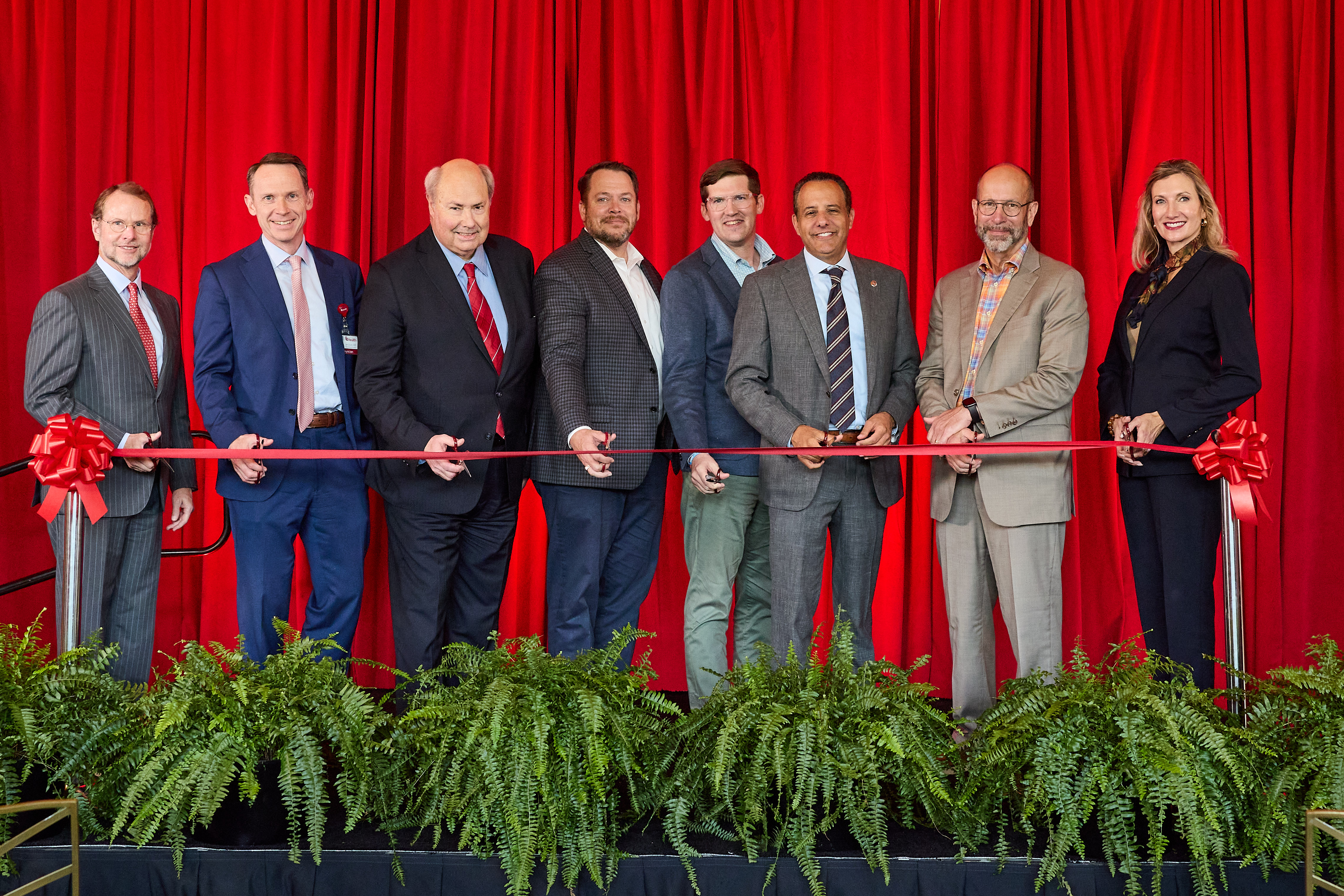 A line of people cutting a red ribbon.