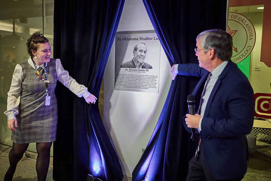 Two people pull aside curtains to unveil a plaque.