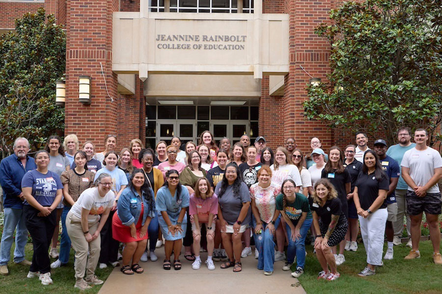 A group of people pose in front of a building.