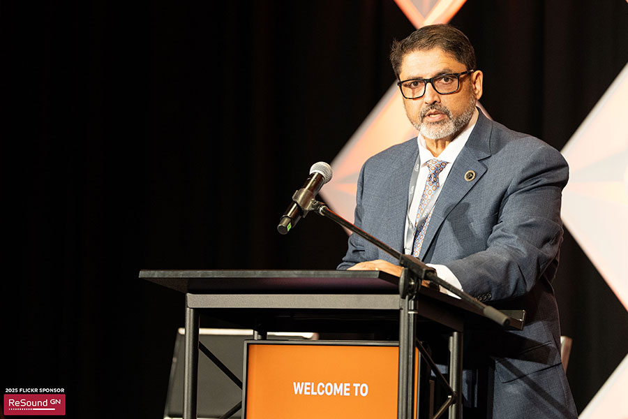 Amyn Amlani standing at a podium speaking.