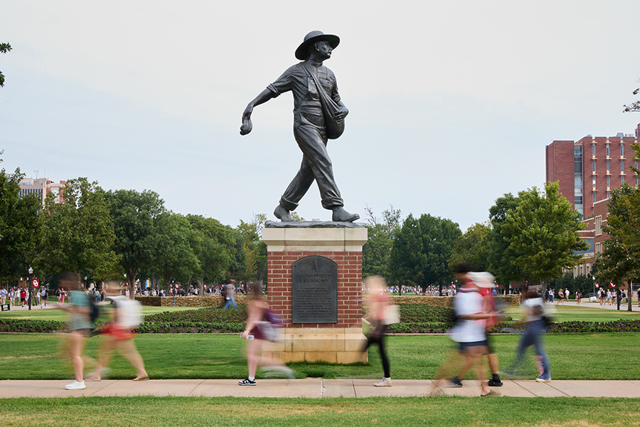 People walking in front of seed sower statue on OU's Norman campus.