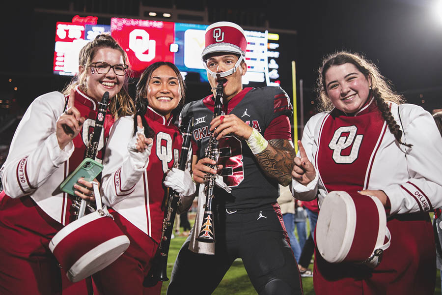 Dillon Gabriel, wearing a marching band hat, and OU Band members pose together with instruments after OU vs West Virginia football game on November 11, 2023.