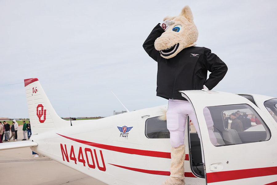 OU mascot stands at the door of a small OU branded plane.