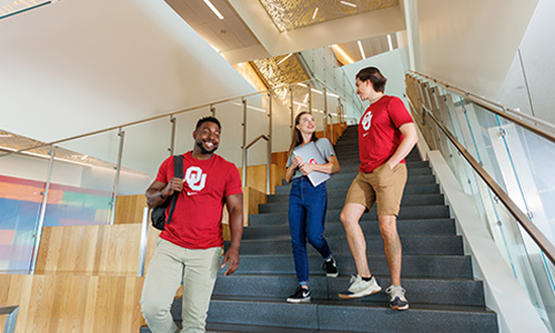 Decorative photo of three OU students wearing crimson shirts and walking down stairs