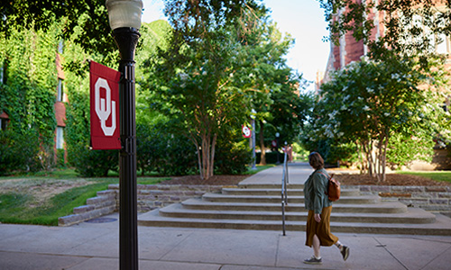 Decorative photo of OU campus as student with backpack walks by