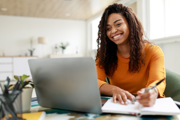Smiling woman sitting at desk looking at laptop.