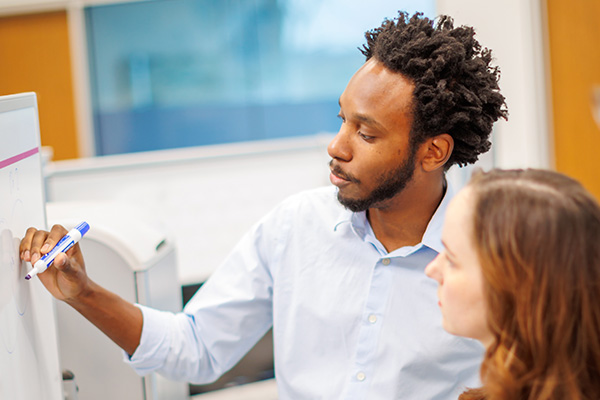 Man and woman working at a white board.