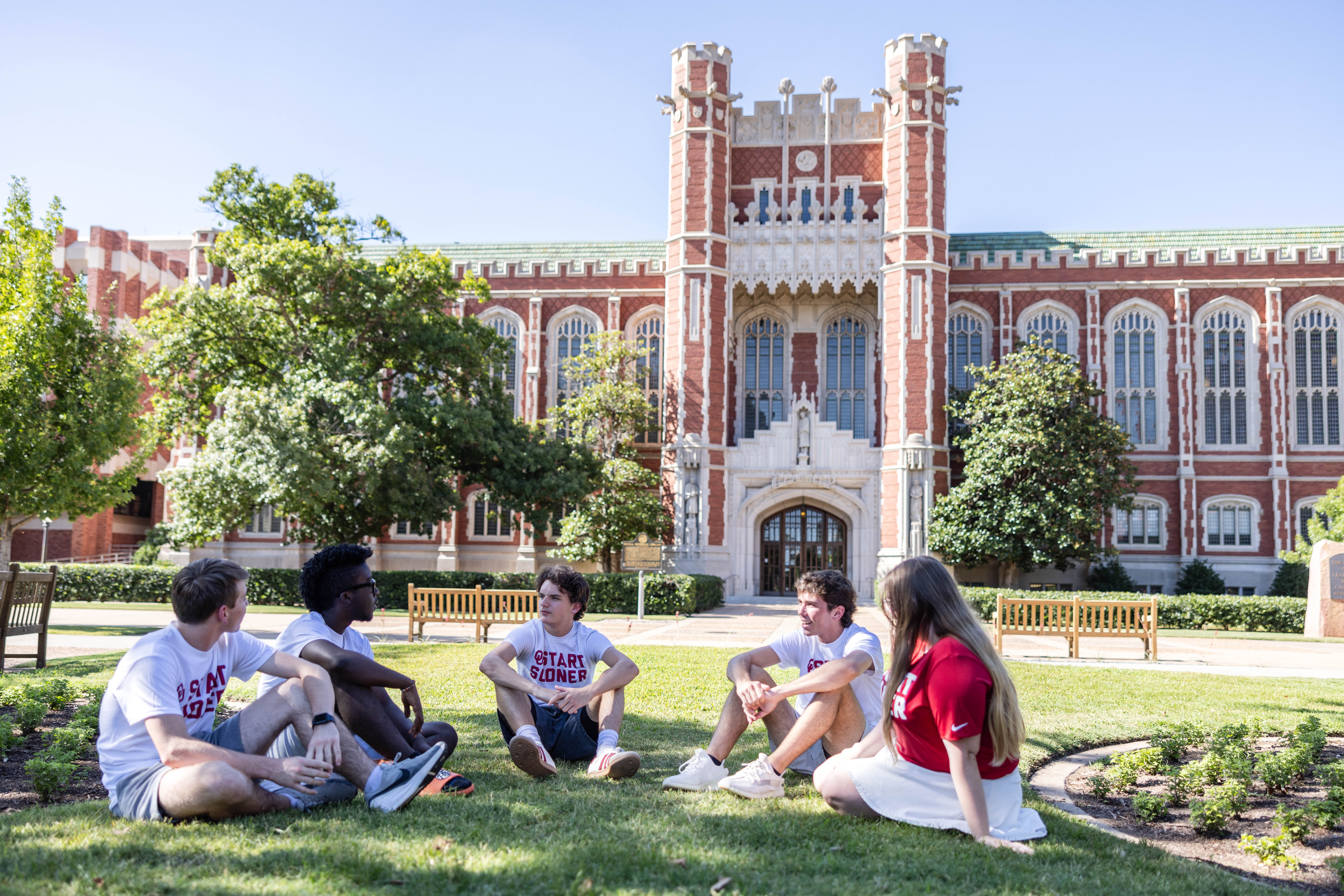 Start Sooner student sitting in the lawn outside of the Bizell Memorial Library