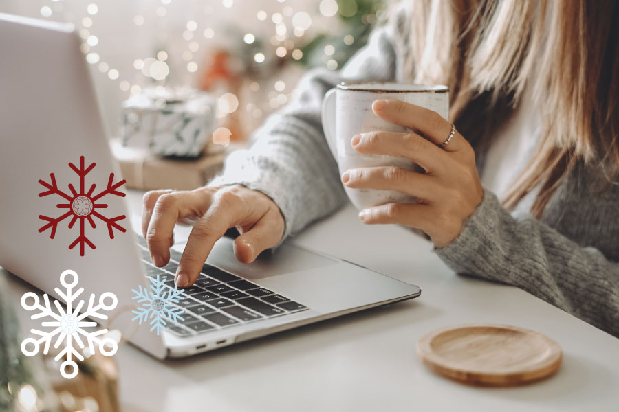 Person typing on laptop surrounded by holiday decorations.