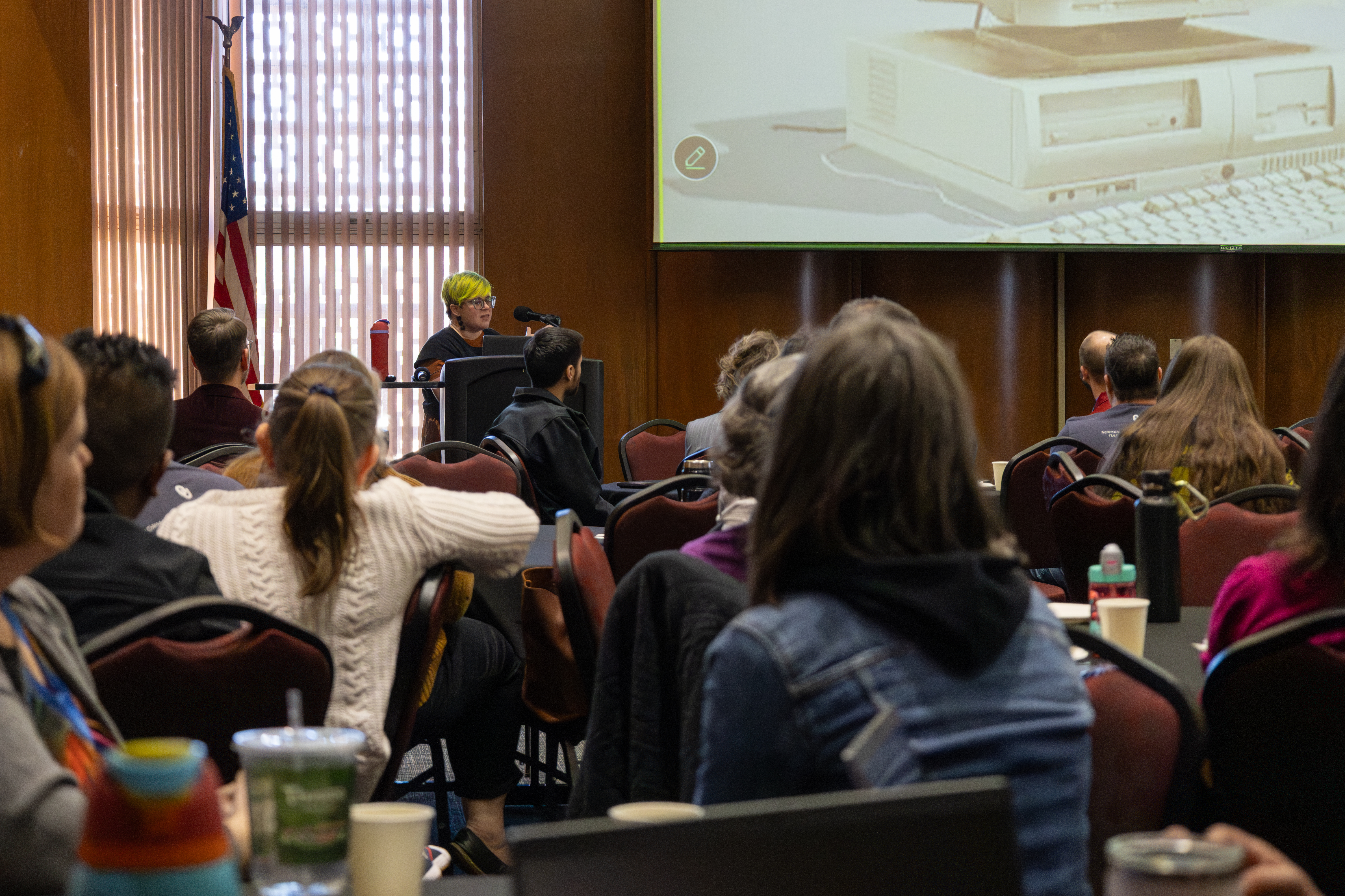 A large group of people sitting at tables listening to a speaker during the Academic Tech Expo.