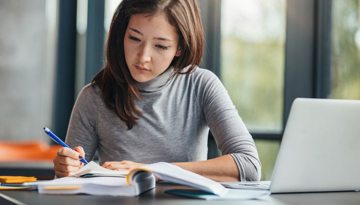 student at desk with notebook and laptop